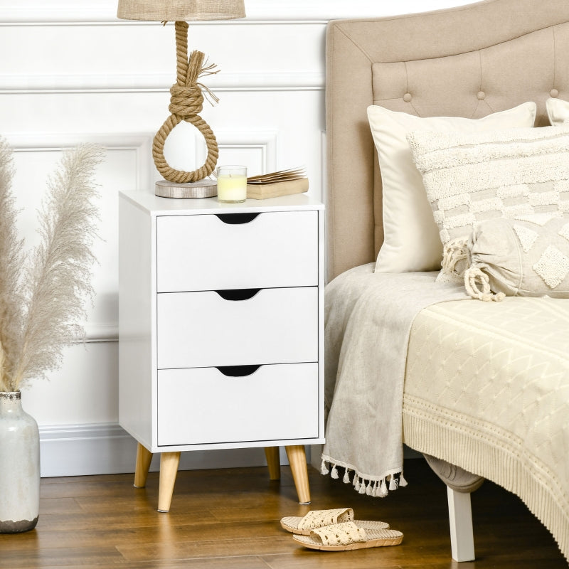 White three-drawer bedside table beside a bed