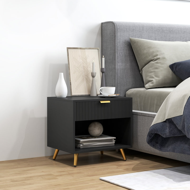 Black bedside table with gold-tone legs beside a bed