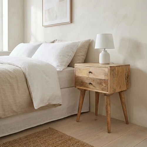 2 Drawer Bedside Table beside a bed with linen bedding, with a table lamp on top