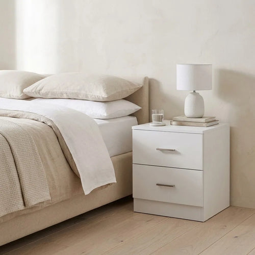 2 Drawer Bedside Table beside a bed with linen bedding, with a table lamp on top