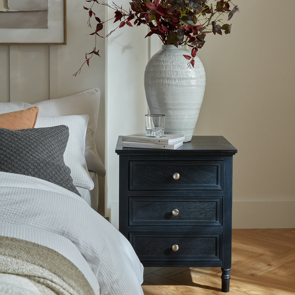 Fowey three drawer table styled beside a bed