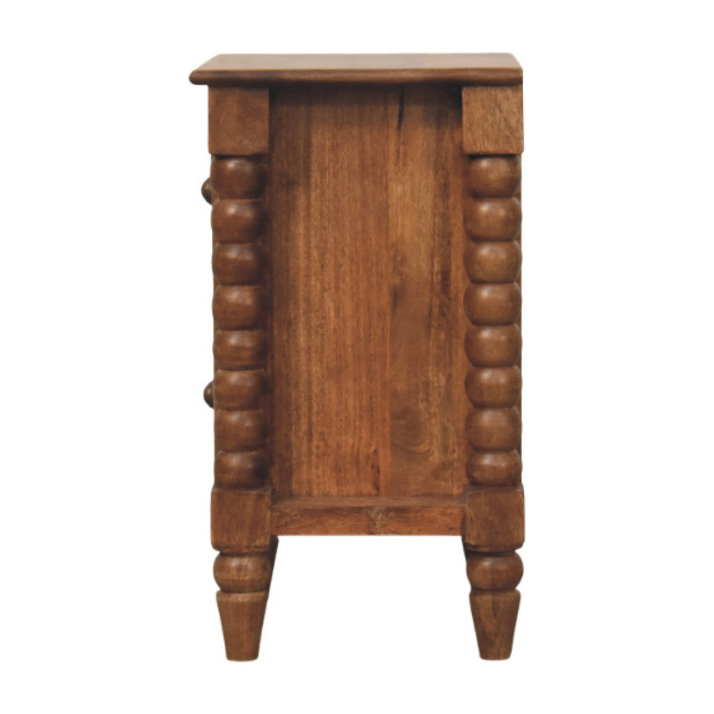 Side view of the amber-brown bedside table with bobbin columns at each corner and turned feet