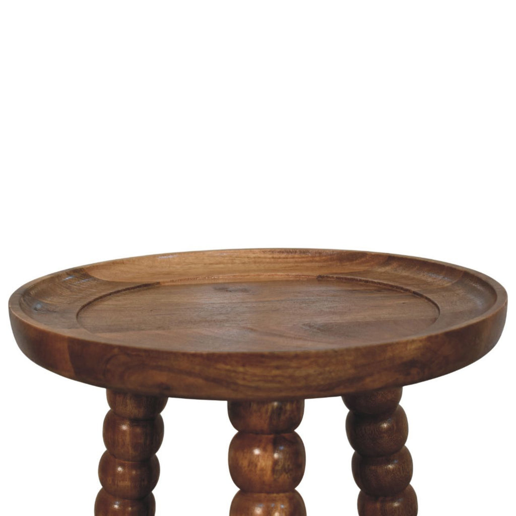 Close-up of the raised tray rim and turned legs of the mango bedside table