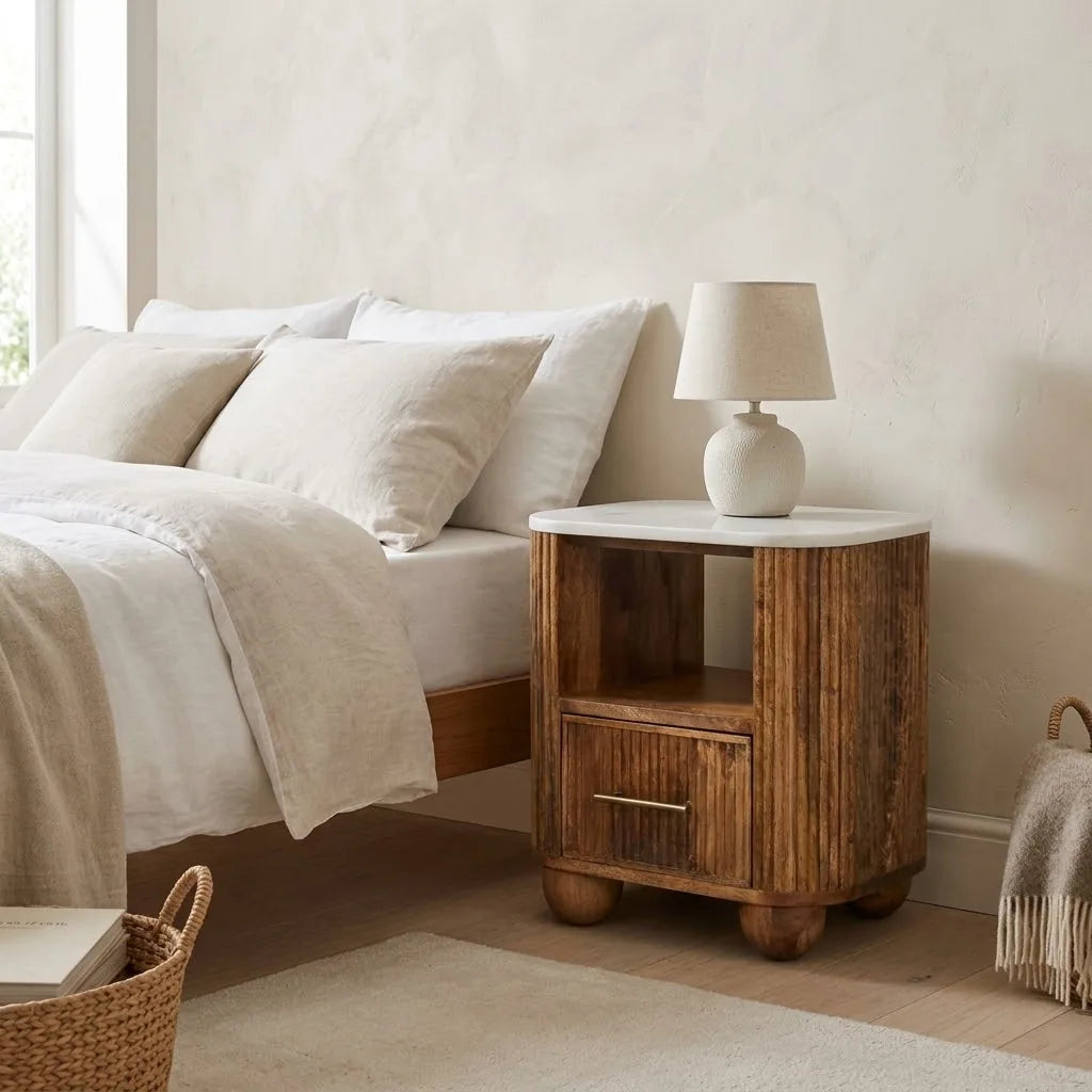 Marble Top Bedside Table beside a bed with linen bedding, with a table lamp on top