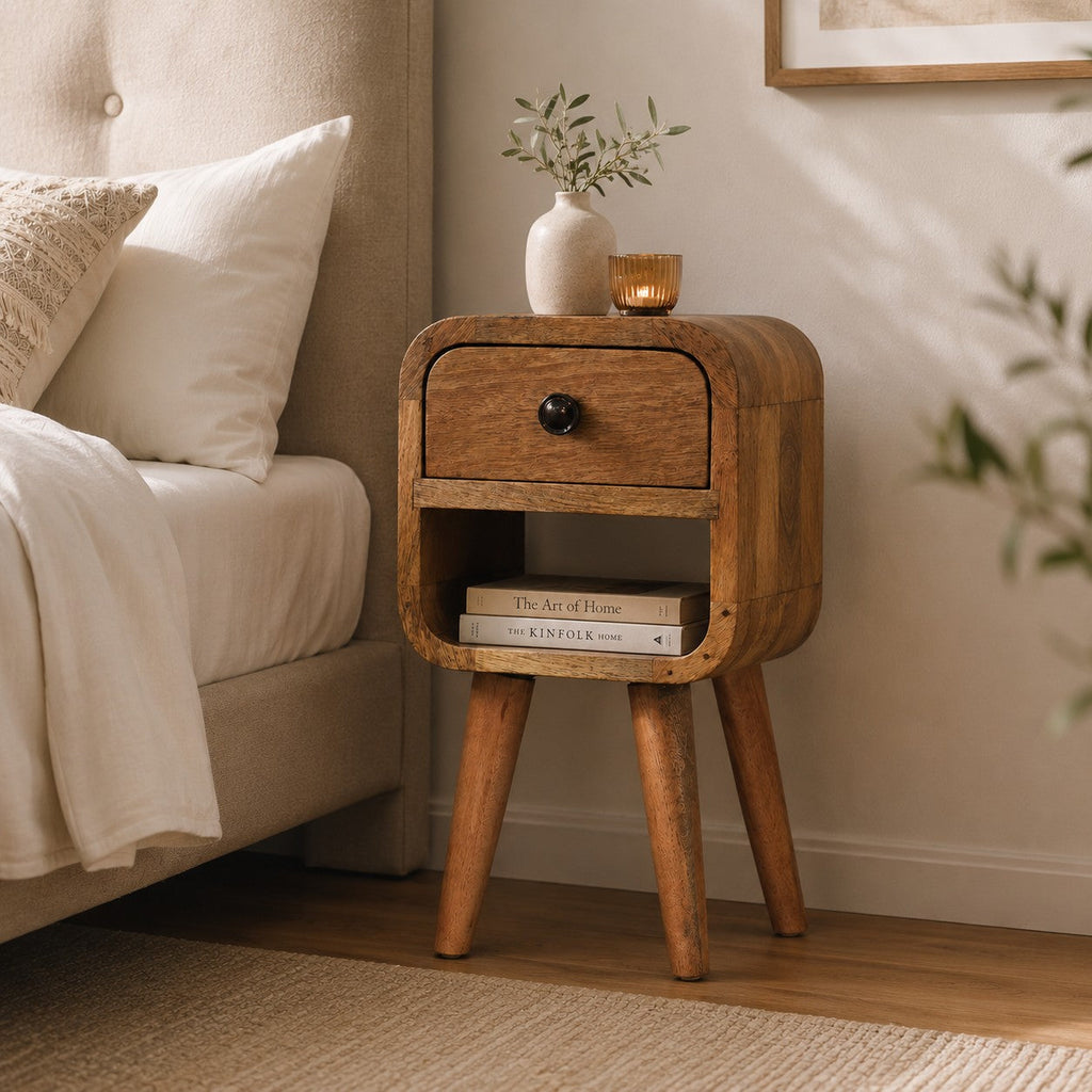 Narrow oak-look bedside table styled in a bedroom setting next to an upholstered bed