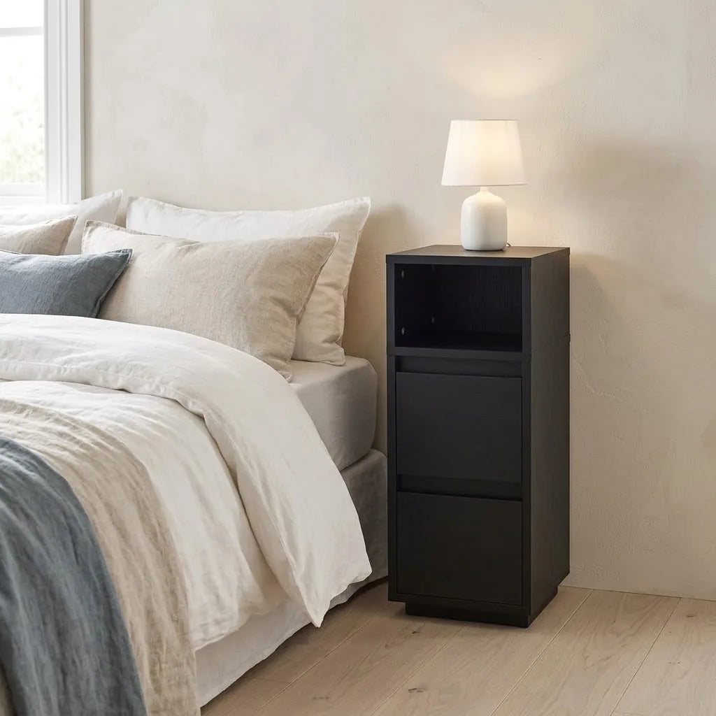 Slim Black Bedside Table beside a bed with linen bedding, with a table lamp on top